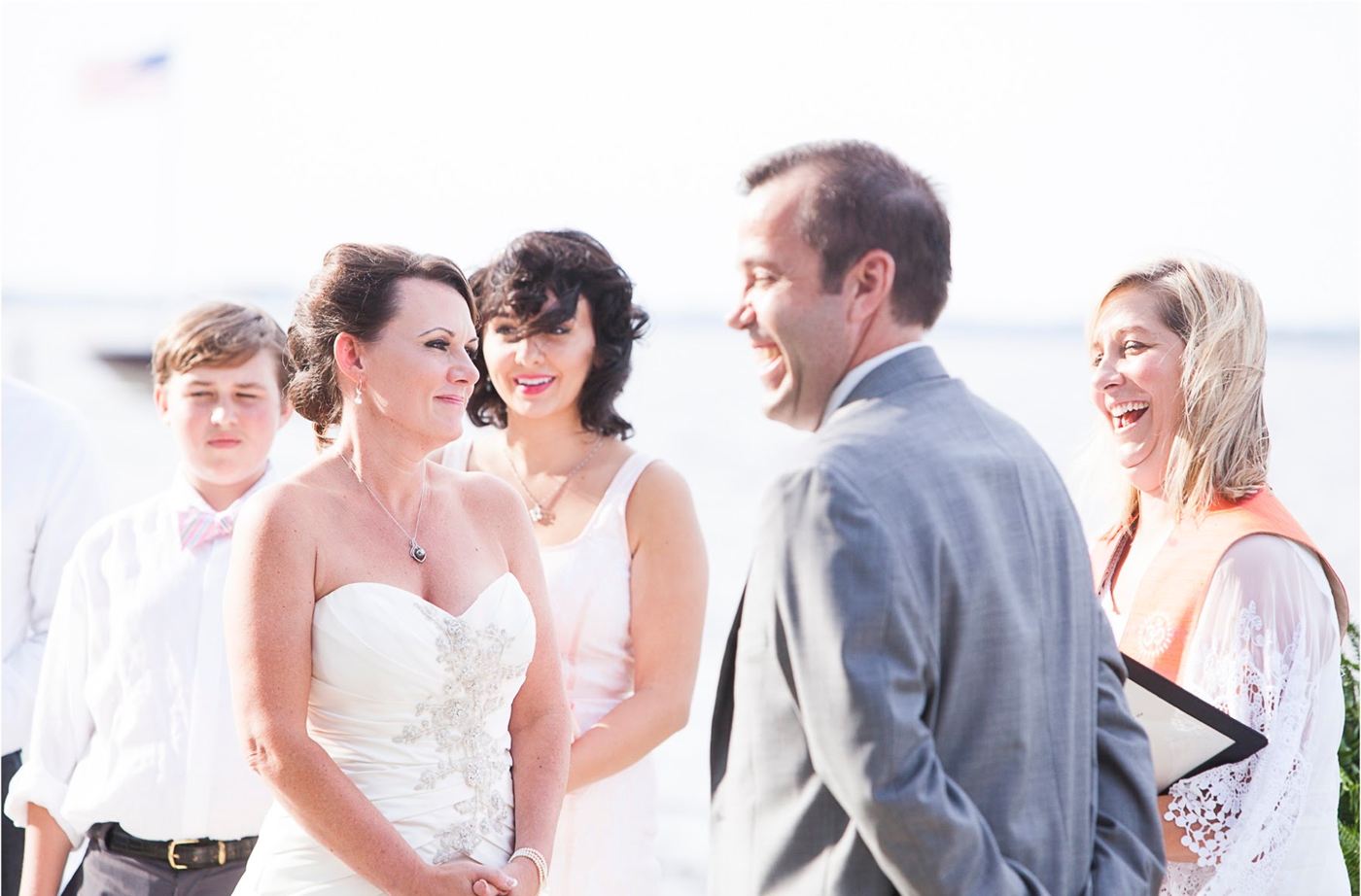 Rev. Christie laughing with a bride and groom during their waterfront ceremony